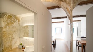 Une salle de bain moderne avec un mur en pierre rustique, un lavabo blanc et un plan de travail en bois.