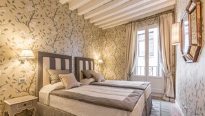 A room with two beds, a nightstand, a mirror, and a window with curtains. - Ca' Dell'Opera Terrace (Venice)