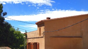 A narrow alleyway with a building featuring a green door and a red and blue sign. - Beautiful village home in the foothills of the Pyrenees (Finestret)