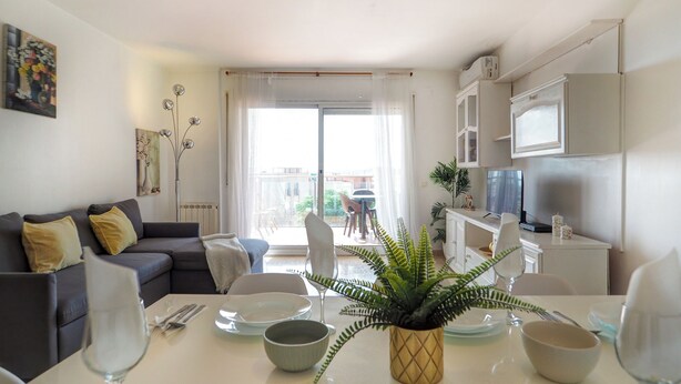 Ein modernes Wohnzimmer mit Sofa, Esstisch und Küchenbereich.