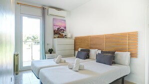 Ein Hotelzimmer mit zwei Betten, einem hölzernen Kopfteil, einem Gemälde, einem Nachttisch und einem Fenster mit Vorhängen.