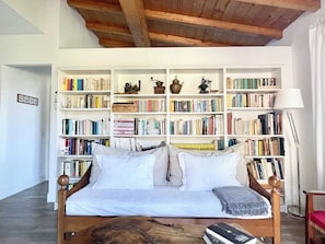A room with a bed, a wooden coffee table, and a bookshelf filled with books and decorative items. - Octo bookcase, sanctuary, organic, design, relaxation. (Imperia)