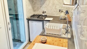 A compact kitchen with a gas stove, a small fridge, a sink, and a wooden countertop. - Octo bookcase, sanctuary, organic, design, relaxation. (Imperia)