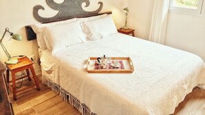 A neatly made bed with a tray of breakfast items, a wall-mounted decorative piece, and bedside lamps. - Octo bookcase, sanctuary, organic, design, relaxation. (Imperia)