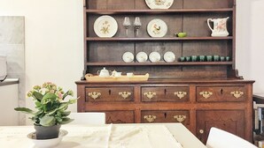A dining area with a wooden buffet cabinet, a table with a white tablecloth, and a potted plant. - Octo bookcase, sanctuary, organic, design, relaxation. (Imperia)