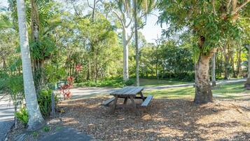 A picnic table in a park with trees and a road in the background.