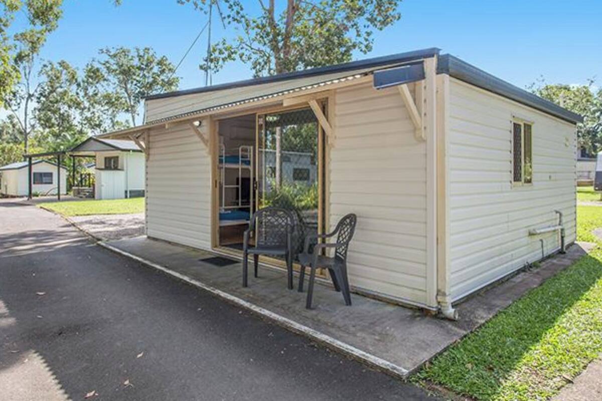 Une petite maison mobile d’un seul étage, dotée d’une véranda et d’une chaise.
