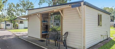 A small, single-story mobile home with a porch and a chair.