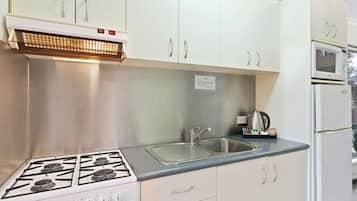 A kitchen with white cabinets, a gas stove, a sink, and a microwave.