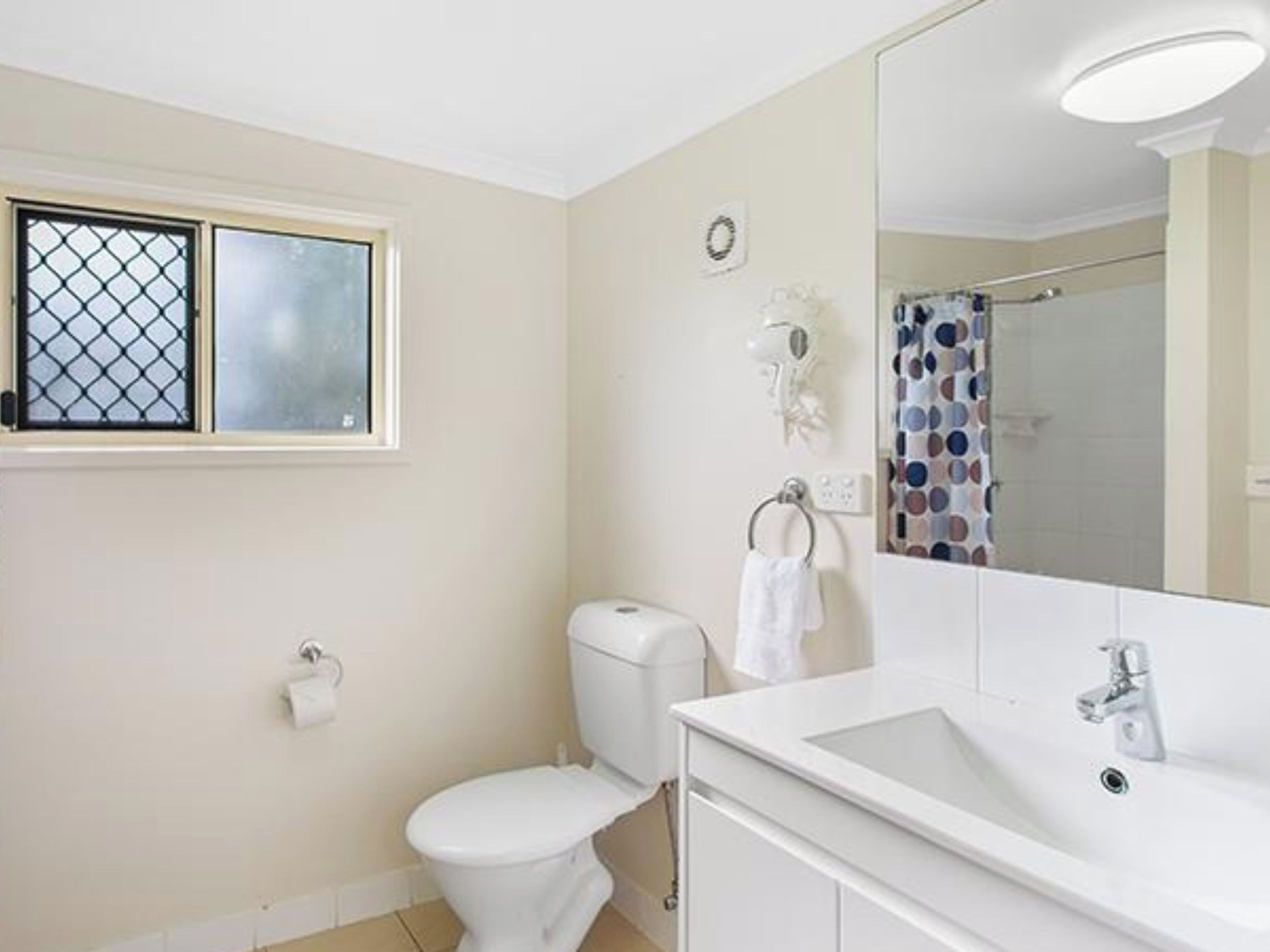 A bathroom with a toilet, sink, and mirror.