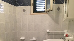 A bathroom with a toilet, bidet, sink, and a window with blinds. - MIMOSA A Three-room detached house in the Villa Carla Residence for realiz (Vieste)