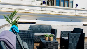 Eine Dachterrasse mit Außenmöbeln und Blick auf ein weißes Gebäude.