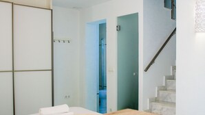 Eine moderne Küche mit einem Holztisch, einer Hängelampe und einer Treppe, die in ein blaues Zimmer führt.