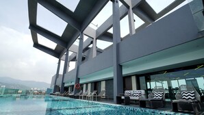 An indoor swimming pool with clear blue tiles, lounge chairs, and a view of mountains in the background. - Jazz Hotel Penang (George Town)