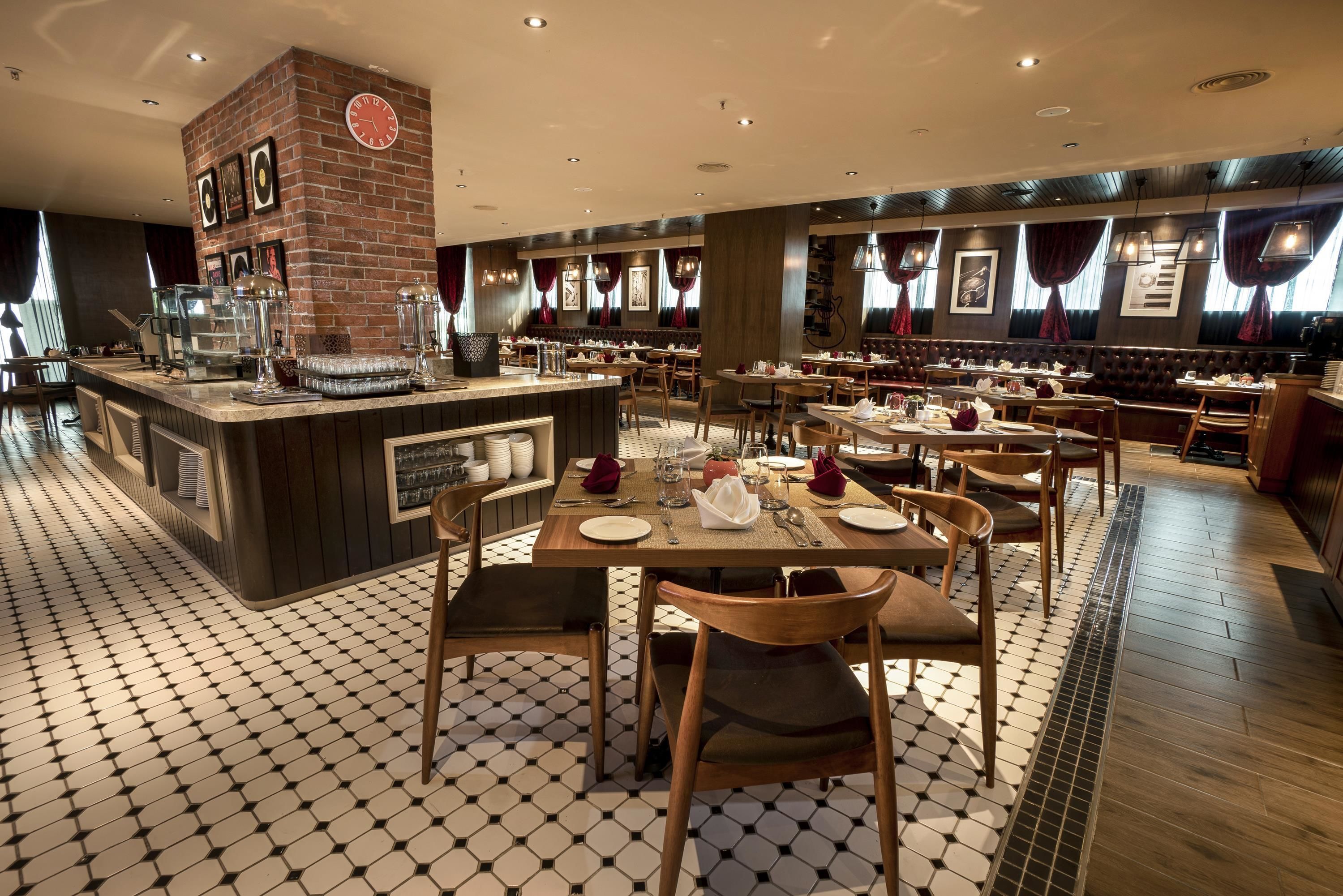 A restaurant with a brick wall, a clock, and a tiled floor.