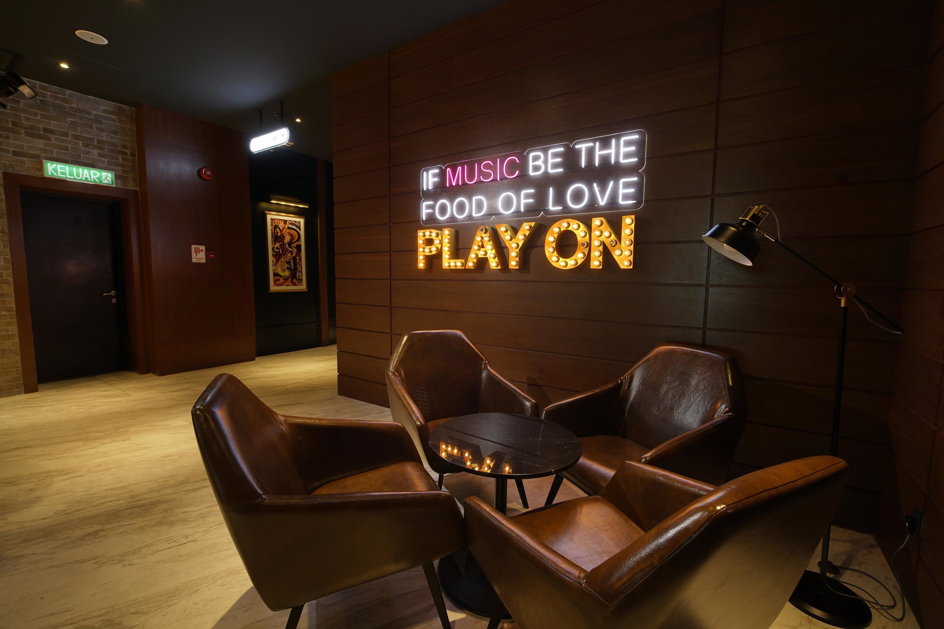 Um espaço PlayOn com poltronas de couro e um letreiro neon.