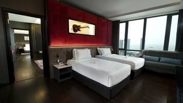 Habitación de hotel con dos camas, una pared de acento roja, una guitarra colgada y vistas a la ciudad.