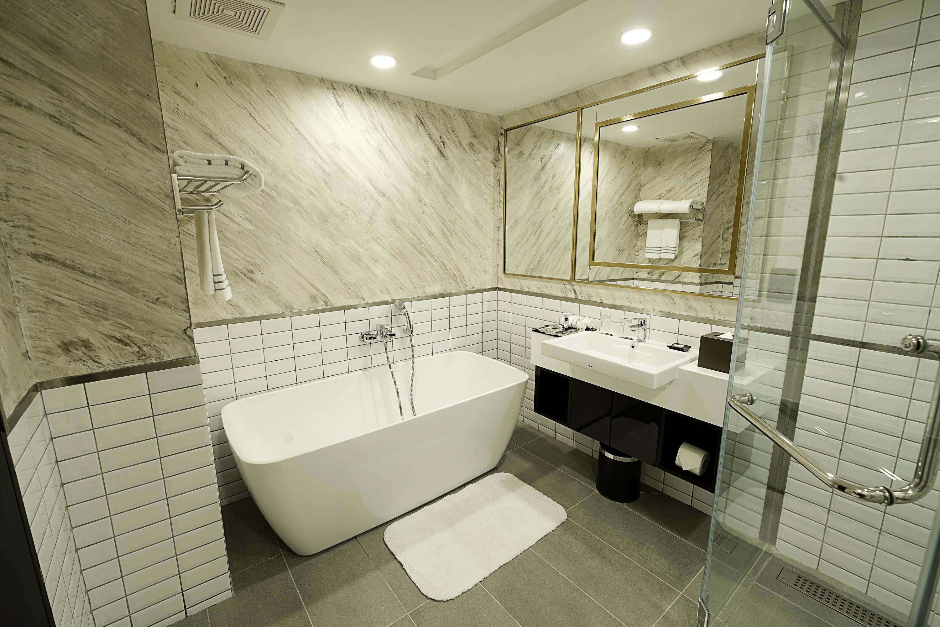 Un baño moderno con una bañera independiente, ducha con cerramiento de vidrio y un espejo grande.