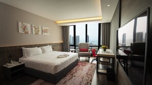A modern hotel room with a large bed, a desk, and a view of the city. - Jazz Hotel Penang (George Town)