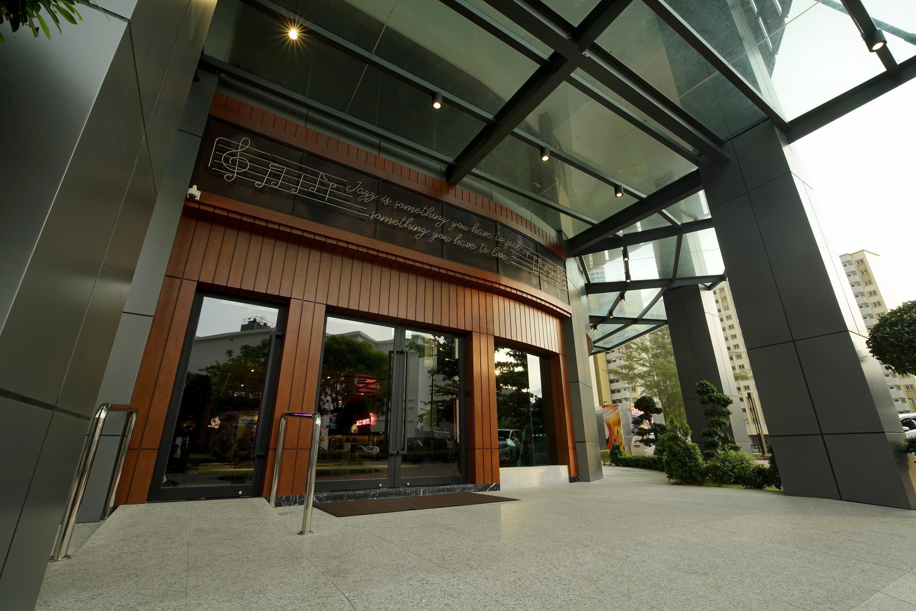 A modern building entrance with a glass facade, wooden accents, and a reflective floor.