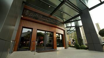 A modern building entrance with a glass facade, wooden accents, and a reflective floor.