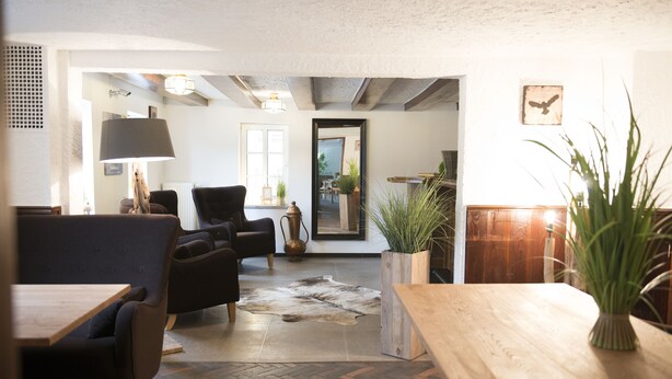 A modern living room with a wooden coffee table, black leather sofa, and a herringbone-patterned floor. - Hotel Garni - Dahlbrucher Hof (Hilchenbach)