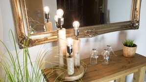 A wooden console table with a mirror, candles, and decorative glass bottles. - Hotel Garni - Dahlbrucher Hof (Hilchenbach)