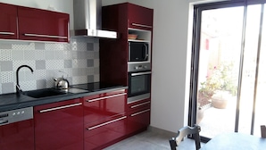 Una cocina moderna con gabinetes rojos, una campana extractora de acero inoxidable, un microondas integrado y un lavavajillas.
