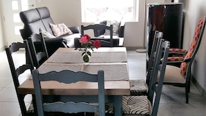 Un comedor con una mesa rectangular, varias sillas con tapicería estampada y una lámpara colgante moderna.