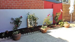Un jardín con plantas en macetas y un banco de madera frente a un muro de ladrillo.