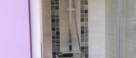 Eine Dusche mit Glastür, Duschkopf zum Halten und einer fest installierten Bedienkonsole.