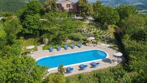 Une piscine avec des chaises longues et, en arrière-plan, un bâtiment en pierre.