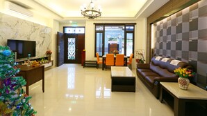 A modern hotel lobby with a marble wall, a chandelier, a television, a Christmas tree, a sofa, and a dining area. - Love Back (Ji'an)