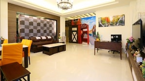 A modern living room with a sofa, coffee table, and dining area. There is a TV, a desk, and a painting on the wall. - Love Back (Ji'an)
