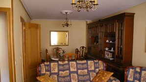Un salon avec un canapé à motifs, un meuble en bois et un lustre.