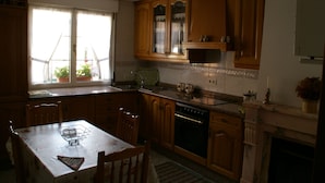 Une cuisine avec des meubles en bois, une table à manger et une fenêtre ornée de plantes en pot.