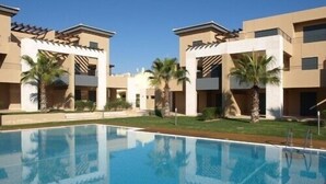 A modern hotel with a swimming pool, palm trees, and a clear blue sky. - 3 Bed Apartment Rental w/ Pool nr Beaches, Golf in Vilamoura, Algarve, Portugal (Vilamoura)