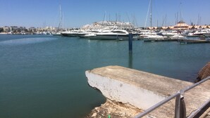 A marina with multiple yachts docked, a concrete pier, and buildings in the background. - 3 Bed Apartment Rental w/ Pool nr Beaches, Golf in Vilamoura, Algarve, Portugal (Vilamoura)