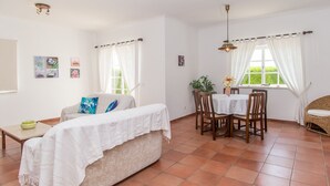 A spacious room with a sofa, a dining table with chairs, and a window with curtains. - Carrell White Villa, Pool, Wifi (Lagos)