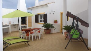 A patio with a table, chairs, a swing, and potted plants. - Carrell White Villa, Pool, Wifi (Lagos)