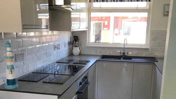 A modern kitchen with a central island, stainless steel appliances, and a window with a geometric curtain. - LEE'S CHALET, NORTON PARK, Dartmouth, 2 bedrooms, sleeps 4 (Dartmouth)