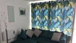 A living room with a sectional sofa, patterned pillows, a framed picture, and a curtain with a leaf design. - LEE'S CHALET, NORTON PARK, Dartmouth, 2 bedrooms, sleeps 4 (Dartmouth)