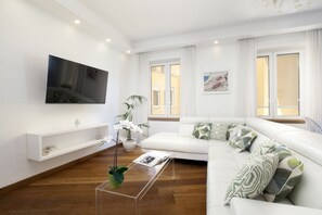 A modern living room with a white sofa, a glass coffee table, a flat-screen TV mounted on the wall, and a potted plant. - Luxury Home Sea View & Jacuzzi in Sorrento centre (Sorrento)