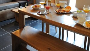 Ein Frühstückstisch aus Holz, eine Couch und ein Fenster mit Vorhängen.