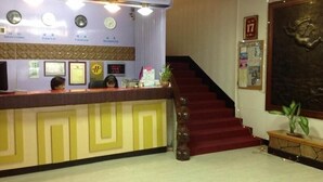 A hotel reception area with a reception desk, clocks, framed certificates, and a staircase. - Reui Cheng Hotel (Kaohsiung)