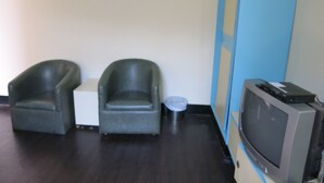 A room with two armchairs, a small table, a television, and a blue wall. - Reui Cheng Hotel (Kaohsiung)