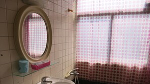 A bathroom with a white sink, a mirror, a glass shelf, and a shower curtain with a polka dot pattern. - Reui Cheng Hotel (Kaohsiung)