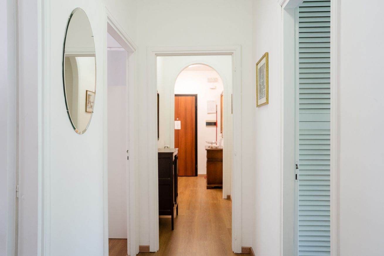 A hallway with a mirror, a door, and a light blue shutter.