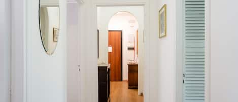 A hallway with a mirror, a door, and a light blue shutter.
