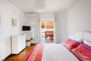 A bedroom with a bed, a TV, a wardrobe, and a desk with a chair.